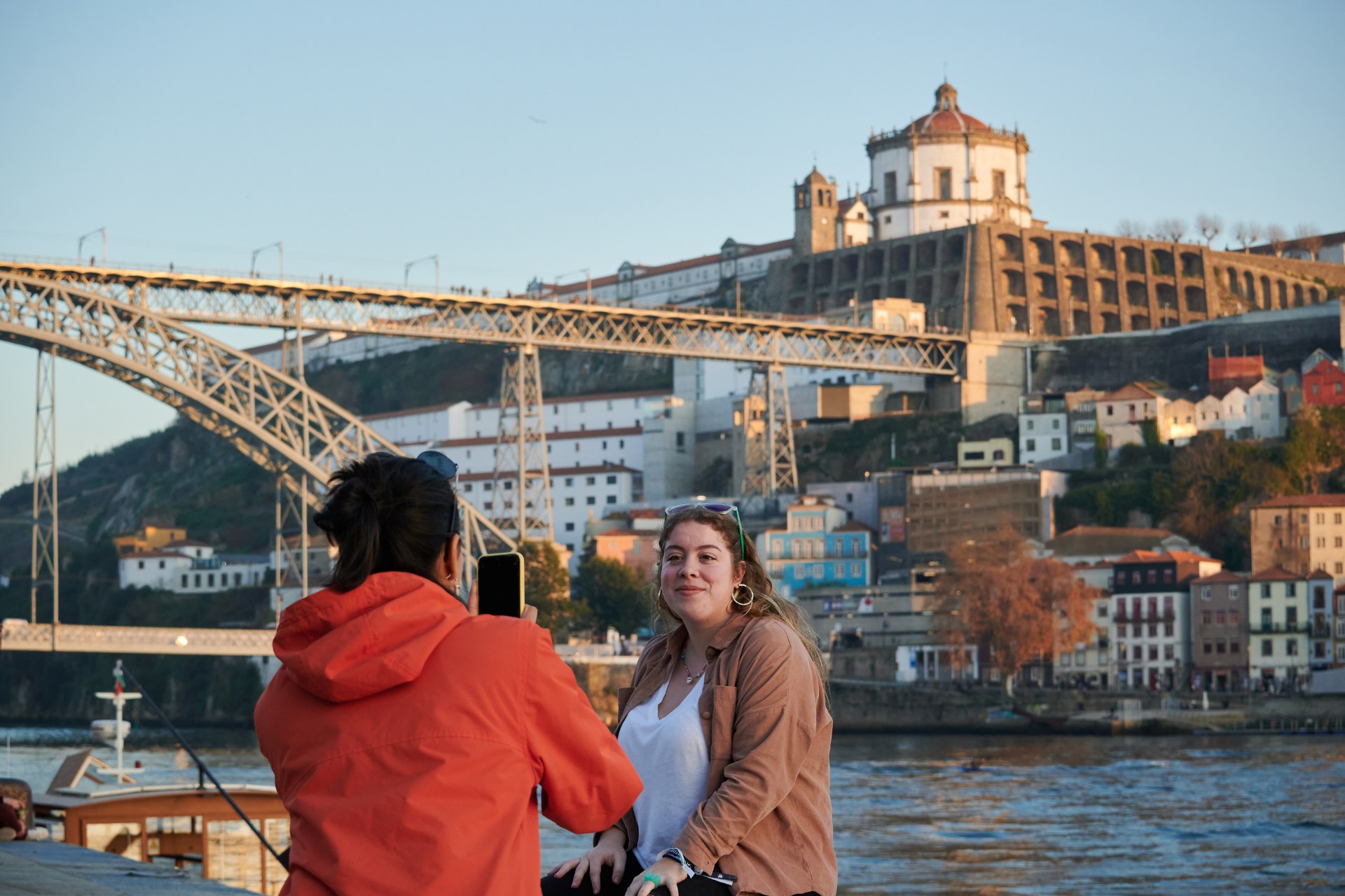 Une jeune femme photographie son amie devant un pont à Porto